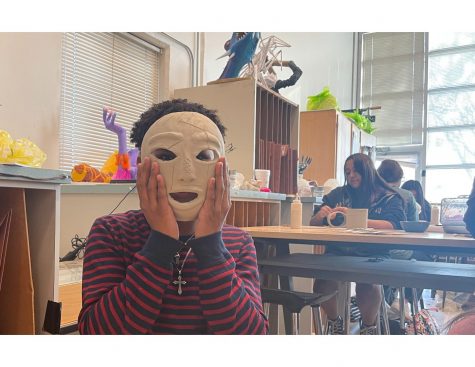 Art 2 student, Tyriek Roye, displays custom ceramic mask that he made in class.