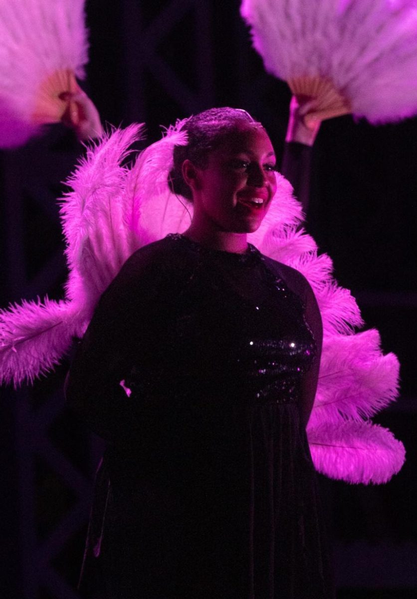 Ensemble member, senior Sydney LaCour, sings and poses with her feather during All I Care About is Love.