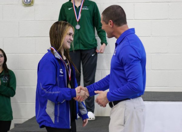 Junior Julianne Armstrong receives her first place medal for the 200 freestyle event from coach Andrew Stewart, making her district champion. 
