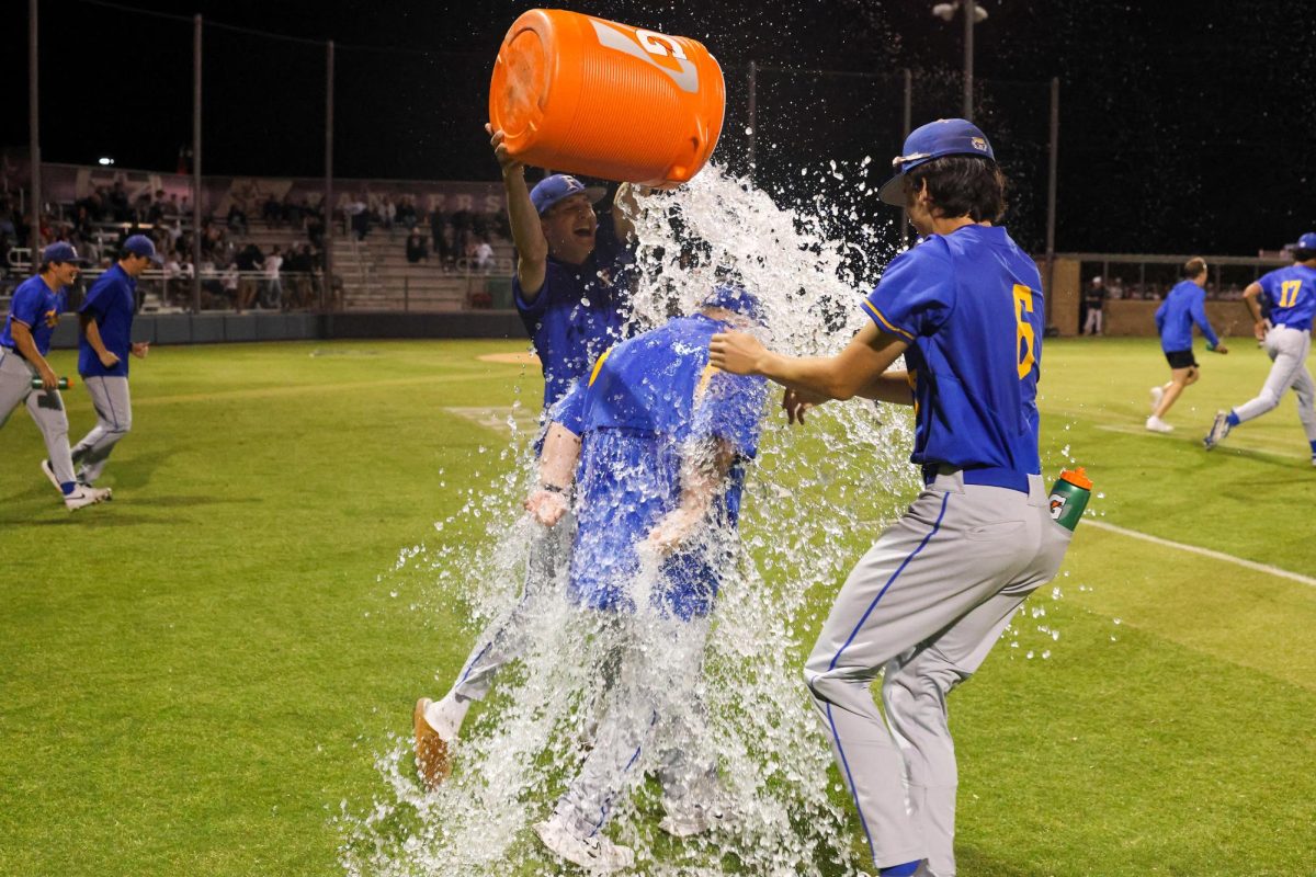 After the win, seniors Austin Clark and Jacob Sparks dump the water bucket onto Assistant Coach Jonathan Woods.