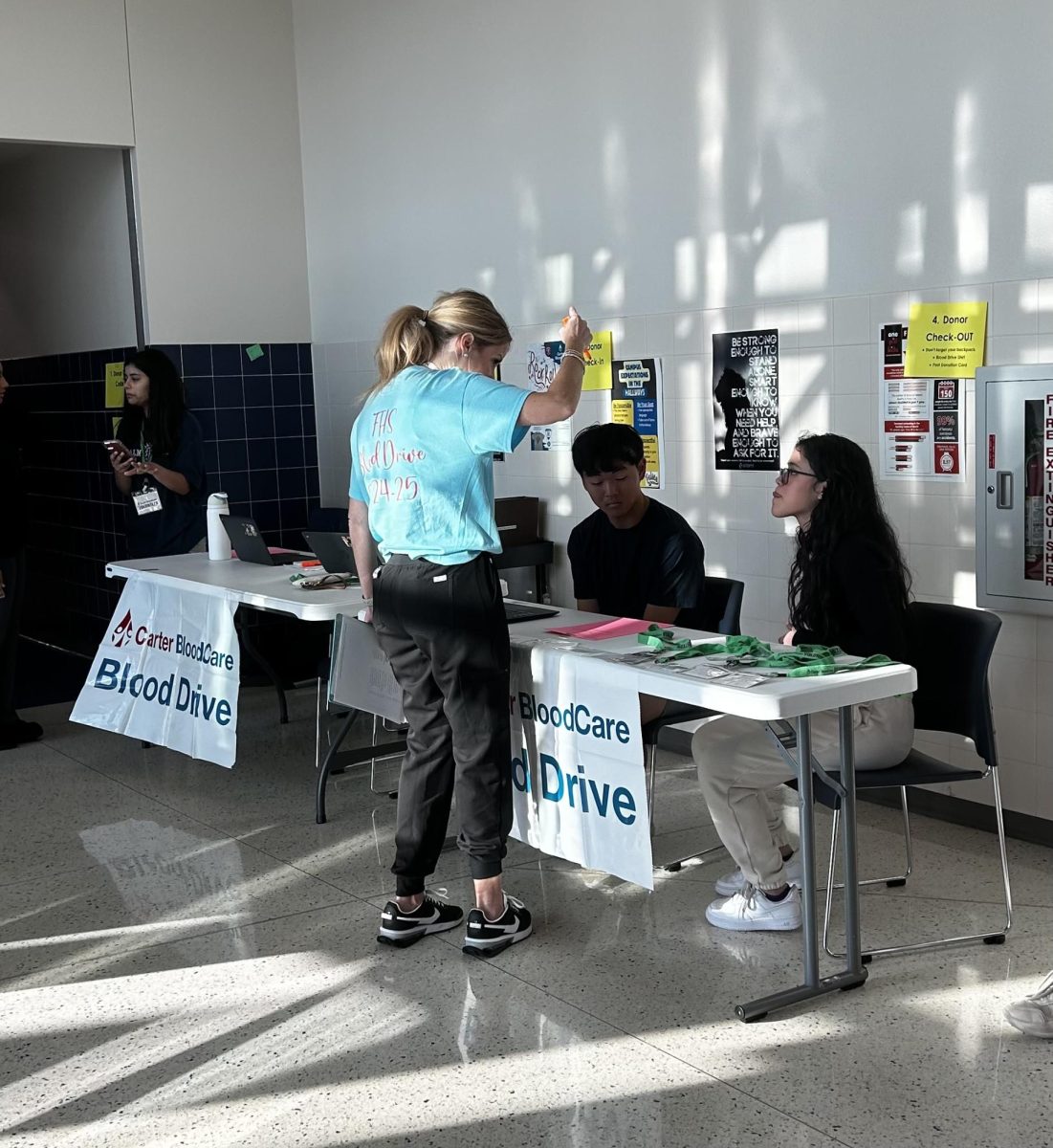 Harbert explains the check in process to two student volunteers before the blood drive starts